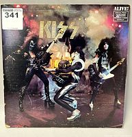 Front cover of KISS 'Alive!' double record album showing band members in stage performance pose with smoky background and album title in illuminated text.
