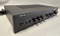 Left angled view of Rotel RA-820A showing top ventilation and front controls including power switch, headphone jack, speaker remote, bass, treble, and balance knobs.