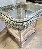 Side view of the vintage rattan/wicker side table showing glass top and woven lower shelf