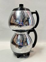Front view of the vintage Sunbeam C30A CoffeeMaster coffeemaker showing the reflective chrome surfaces, black handle, knob on top lid, and base controls.