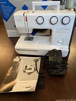 Bernette B35 sewing machine front view with manual and black foot pedal placed in front.