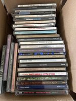 Photo showing stack of various music CDs including Michael Buble, Leonard Cohen, Susan Boyle, Jeff Foskett, and others inside a box