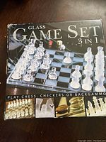 Photo of the box showing the glass 3 in 1 game set, illustrating the chess pieces on the board and promotion of playing chess, checkers, or backgammon.