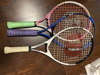 Top-down view of three kid tennis rackets stacked to show grips and string area.