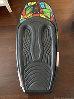 Top-down photo showing the full kneeboard with colorful design and padded black knee area.