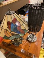 Tiffany style stained glass lamp next to black fabric shade lamp on wooden surface