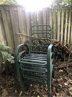 Green metal framed lawn chairs stacked, showing front and side views. Chairs are without cushions and have curved armrests and slatted seat and back elements.