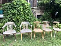 Photo showing all five wooden chairs arranged on grass with garden background, highlighting weathered outdoor condition.