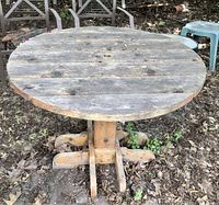 Front view of round wooden table with visible weathering and central hole for umbrella.
