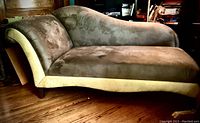 Side view of the chaise lounge showing grey faux suede fabric and yellow detail on the bottom edge, highlighting shape and condition.