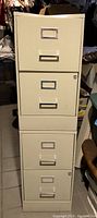 Stacked two-drawer beige metal filing cabinets showing front view with handles and locks