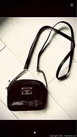 Full view of black Michael Kors crossbody purse showing leather and chain strap, rectangular shape with logo plate front