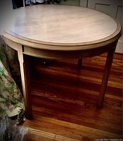 Full view of round wood table with bleached finish showing four straight legs and overall condition
