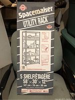 Photo of the boxed Spacemaker Utility Rack showing the brand, model, shelving details, and measurements.