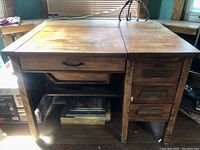 Full view of vintage solid wood sewing desk showing bifold top, drawers, and lower open shelf.