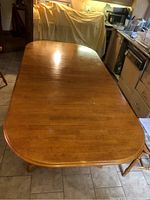 Top view of solid wood oval dining table showing glossy finish and surface marks.