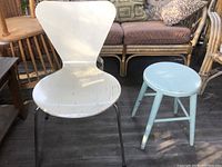 White wooden chair with metal legs and light aqua round wooden stool together, showing paint wear and condition.