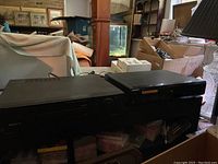 Shows two black Sony players side-by-side on a shelf, one labeled VCR and the other DVD/CD player, with cables attached.