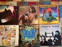 Six vintage rock albums lying flat including Styx - Cornerstone, Peter Frampton - I'm In You, Jefferson Starship - Spitfire, Al Stewart - Year of the Cat, Foghat - Energized, and Paul McCartney - London Town.