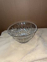 Crystal punch bowl angled to show outer side with cut patterns and scalloped rim.
