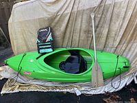 Full side view showing kayak hull, deck bungee cords, mounted life jacket and paddle