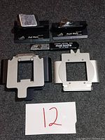 Overview of two Logan mat cutters, Logan mat knife, and metal framing holders on carpeted floor with item number 12 shown on paper.