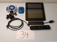 Vizio tablet, small blue GoPro style camera, waterproof case, USB charging cable, Amazon Firestick with Alexa voice remote.