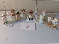 Wide view of all figurines including 5 Willow Tree style wooden female figurines, angel, boy figure, child figures on base, and rocking horse.