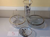 Overview of the set including two crystal bowls with silver rims, one flower vase, and one trinket dish shaped like a seashell