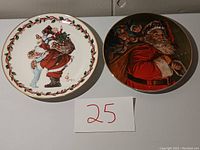 Two decorative Christmas plates shown side by side on a flat surface, one white background with Santa and child, the other darker with Santa carrying toys.