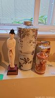 Full view of the figurine and the three vases on a table by a window