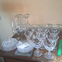 Wide view of multiple clear glass stemmed bowls, plates and serving dishes arranged on a table.