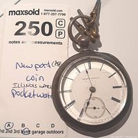 Front view of Illinois pocket watch showing white dial with black Roman numerals, small seconds dial, attached wind-up keys, and some wear on the case.