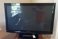 Front view of the Panasonic 42-inch Plasma TV showing screen and remote on stand.