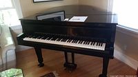 Front corner view of black Yamaha G2 baby grand piano showing keyboard and legs