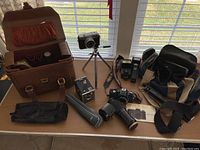 Wide shot of all camera equipment on table including cameras, flashes, bags, and accessories.