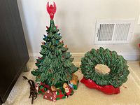 Photo showing ceramic Christmas tree and wreath unlit with power cords visible.