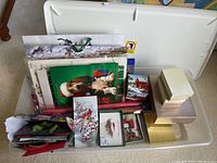 Photo showing all Christmas wrapping supplies and storage bin from a top view, displaying gift bags, wrapping paper, cards, decorative boxes inside the bin.