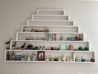 Full view of five-tiered white wall shelf holding various figurines and knickknacks, organized by shelf.
