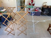 View showing the two wooden accordion-style drying racks and one white metal drying rack with wire lines positioned in a room.