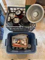 Milk crate filled with black and red flashlights and lanterns, including a large aluminum reflector with bulb socket.