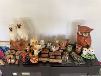 Wide shot showing entire collection of owl figurines and salt and pepper shakers on a cabinet top.