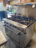 Front perspective view of the Imperial industrial gas stove showing six burners and oven door with handle and control knobs.
