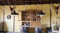 Wide view of the two hanging pendant lamps in a rustic room with a bar setup.