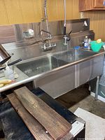 Overall view of stainless steel double basin sink with backsplash, faucet and sprayer.