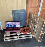 Wooden pallets, Milwaukee sawzall kit in red metal case, electrical cord, and wooden chalk sign board