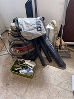 Overall view of the Shop-Vac unit, accessories including hoses, and small tool tray on a floor