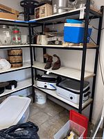 Two black metal storage shelves holding various household items. Shelves measure 48x18x72 inches. Contents are not included.