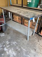 Overall view of dirty metal utility table showing conservation condition and lower shelf.