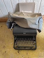 Front view of the vintage Royal typewriter with dust cover placed on top and a Southworth box behind it.